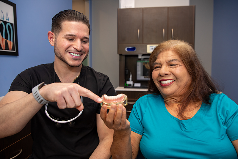 Dr. Perez and patient looking at a full arch implant prosthetic